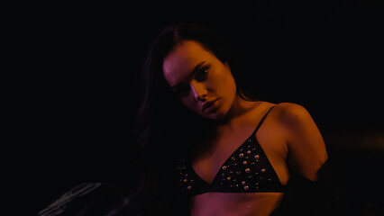 Obraz na płótnie Canvas Sexy woman in bra looking at camera on black background.