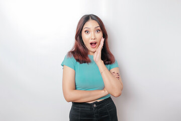 A portrait of a shocked Asian woman wearing a blue t-shirt, isolated by a white background