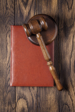 Wooden gavel and red law book on table top view