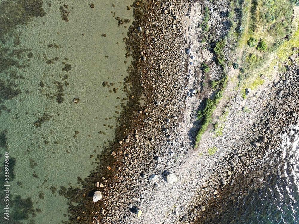 Sticker aerial drone view of an island surrounded by clear sea, beautiful coastline on sunny day