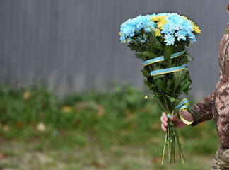 Soldier holds flowers. A funerals of Ukrainian servicemen.