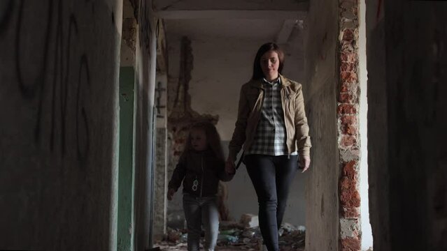 Terrible premises and ruins, the result of the war in Ukraine, a destroyed house, a mother walking down the corridor, holding a child by the hand