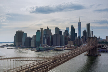 Fototapeta premium Manhattan in background along East River with picturesque Brooklyn Bridge New York City United States from panorama aerial view.