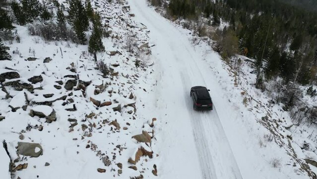 Rovaniemi, Finland - october 15, 2022 Flying a drone behind a car in the winter mountains. jeep grand cherokee wk2 in the snow in the forest . top to bottom view