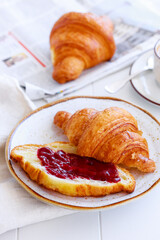Classic french breakfast with croissant with jam, coffee and newspaper