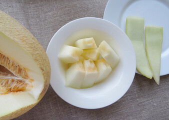 Cut open cantaloupe melon , sweet melon with seeds close up  , Slices of juicy and tasty melon on a white plate. Top viewOrganic summer natural background Photo