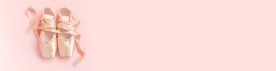 Nieuwe pastel beige balletschoenen met satijnen lint geïsoleerd op roze achtergrond. Ballerina klassieke spitzen voor danstraining. Balletschoolconcept. Bovenaanzicht plat lag kopie ruimte banner