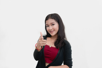 An Asian teenager smiles while pointing at the camera doing a "you" hand pose for a studio shot isolated on a plain white backdrop.