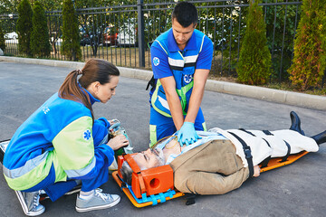 Personnel of emergency service provide first aid to victim with medical equipment, give heart...