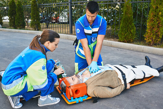 Personnel of emergency service provide first aid to victim with medical equipment, give heart massage and CPR to patient to save his life. First aid, ambulance