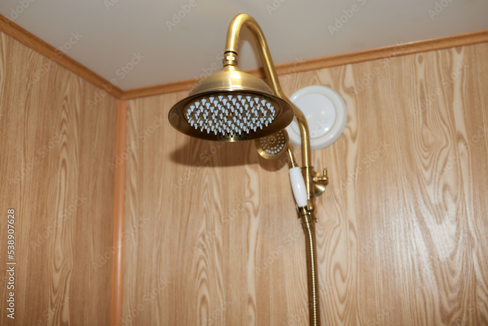 Wall mural Gold colored bathroom shower faucet. Shower head with ceramic handheld.