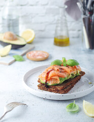 A rye bread sandwich with avocado and salmon