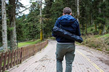 Fototapeta premium Young hiker man hiking in the mountain during autumn season. Young hiker man with cargo pants carrying tent on his back and walking in the forest
