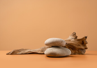 Mockup stage for advertising made with stones and weathered snag on a sandy background with copy space. Natural pedestal for cosmetic product presentation or package advertisement.