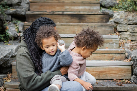 Black mother with her biracial twins on stairs in backyard in fall 