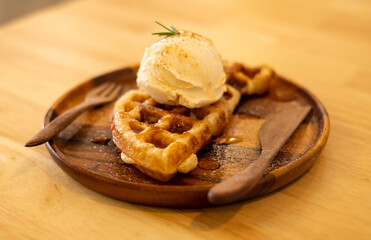 Waffle dessert plate decorated with ice cream on a wooden plate