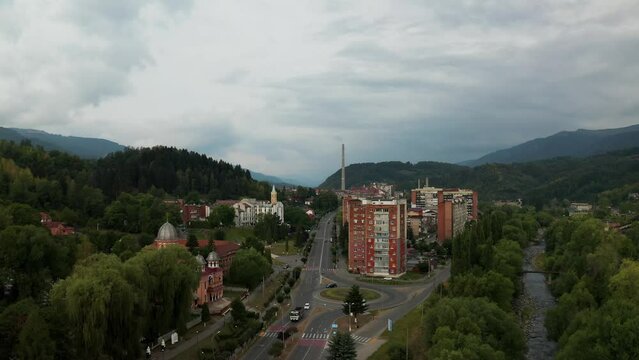 Aerial top-down 4k view over a small Romanian town, in the area of Hunedoara. Cinematic drone shot flying over a gravel road in pine trees in Lupeni town surrounded by mountains. Aerial view, Lupeni, 