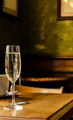 Sparkling wine in a glass with bubbles on the background of a vintage house.