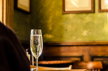 Sparkling wine in a glass with bubbles on the background of a vintage house.