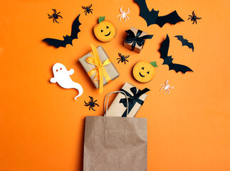 Brown paper shopping bag with Halloween decorations on orange background.