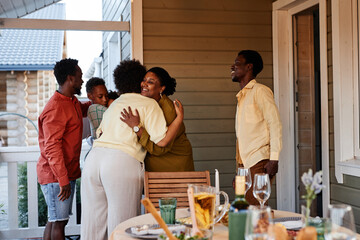 Portrait of African American family embracing outdoors welcoming guests for house party