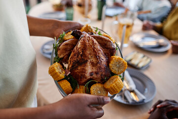 Close up of African American woman bringing homemade chicken dish to table at family gathering