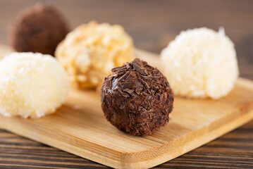 Brigadeiro, Brazilian truffle made with chocolate, coconut and cashews on a wooden board.