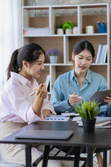 Two young Asian women discuss the concept of a new start-up project. analysis of financial planning and statistics and investment market on laptop computers