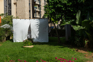 Jewish festival of Sukkot in Israel. Traditional sukkah with handmade decorations near the building on the street. 