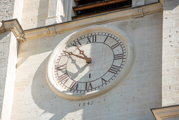 Old clock with Roman numbers engraved on the facade of bell tower of Notre-Dame-des-Anges Collegiate Church in L'Isle-sur-la-Sorgue. France
