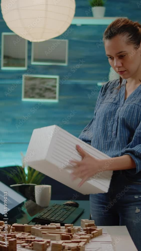 Poster vertical video: woman architect checking blueprints and maquette analyzing model for construction la
