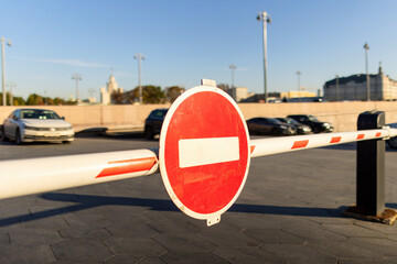 Red round stop sign on an automatic entrance gate on a parking lot © Aguus