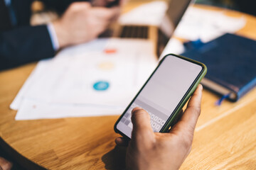 Crop man using cellphone at table