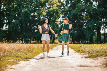 Young pretty girls walking in the park and holding hands