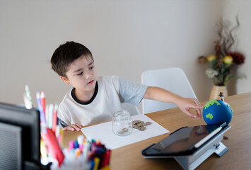 School kid pointing finger at world map and putting money coins into clear jar, Child saving money for travel, Children learning about saving for education and future concept