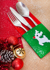 Christmas flat lay with red serviettes and playful reindeer cutlery setting on rustic burlap fabric with copy space