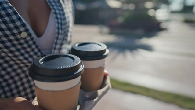 A close up of a woman hands in blue shirt holding a carry tray with two cups of morning fragrant coffee. High quality 4k footage