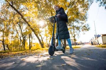 young girl with long coat riding an electric scooter