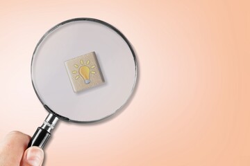 Magnifying glass with lamp bulb icon on cube