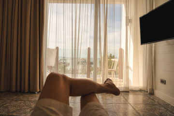 Man relaxing cross legged in bedroom with sunshine through curtain in the morning