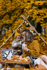Happy family on a beautiful fall picnic in the park. Cozy autumn vibes. Young father, mother and their cute son spending quality time together, having fun. in the park