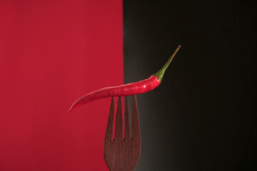 red chili Pepper on wooden fork on black background