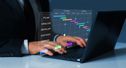  Project manager working on laptop and updating tasks and milestones progress planning with Gantt chart scheduling interface for company on virtual screen.Business Data Management System.