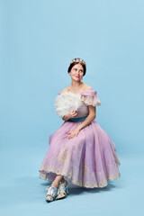 Shyness. Young elegant girl in lilac color medieval dress as young queen or princess on blue background. Eras comparison, beauty, art, emotions and vintage fashion style © master1305