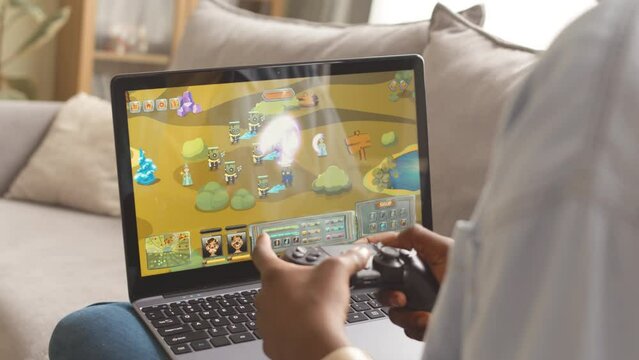 Cropped shot of unrecognizable African American gamer girl playing exciting online rpg game on laptop using controller