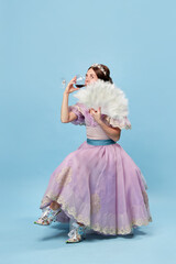 Tasting wine. Cute young girl in lilac color medieval dress as young queen or princess on blue...
