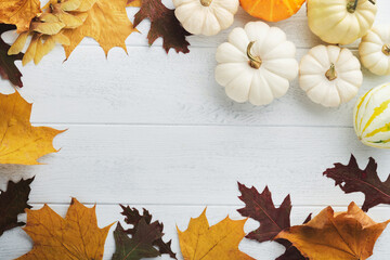 Halloween festive autumn background. Autumn decor from pumpkins, berries, maple leaves and chestnuts on old rustic white wooden backgrounds. Concept of Thanksgiving day Halloween. Top view copy space