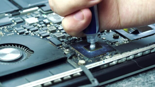 Computer technician applies thermal paste from a syringe on a cpu or gpu for better air cooling. Computer repair service