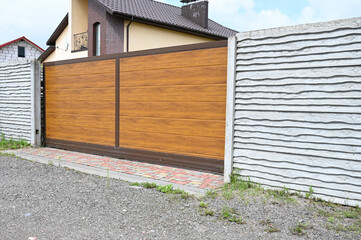 Automatic entrance gate used in combination with a wall made of concrete. Fence and the modern house