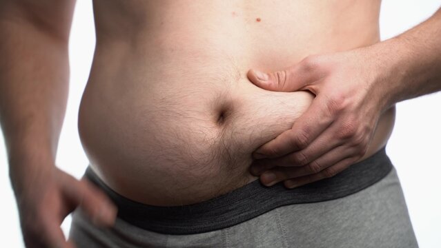Man squeezing his plump belly over isolated background